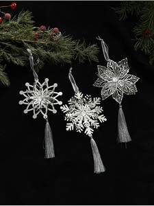 Close-up of silver hollow snowflake ornaments with grey tassels and pine branch decor