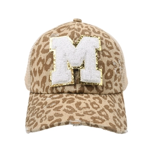 Dettaglio della lettera M in ciniglia con bordo glitter oro su cappello leopardato