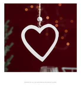 Close-up of white wooden heart ornament with twine hanger on festive red background