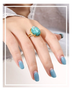 Close-up of golden ring with oval turquoise stone and sparkling side diamonds