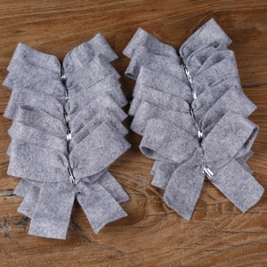Detail of grey felt decorative bows with silver metal clips on rustic wooden background
