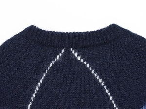 Macro detail of dark blue knit sweater showing round neck and white geometric pattern