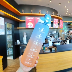 Close-up of a blue and orange gradient sports bottle with time markers held in a cafe
