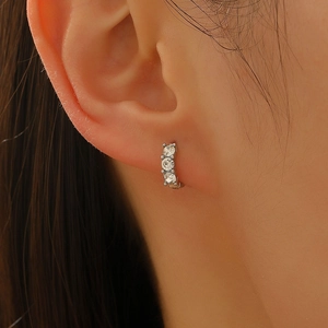 Three-stone silver hoop earrings with clear round zircons in a minimalist luxury style