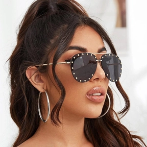 Detail of oversized pilot sunglasses with gold metal studs and smoky gray lenses