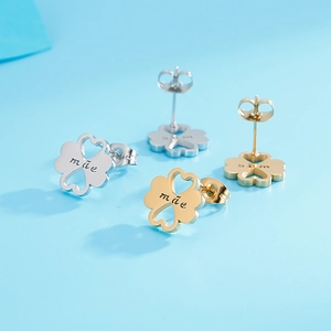 Close-up of gold and silver four-leaf clover stud earrings with mother engraving