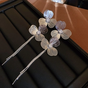 Détail de boucles d'oreilles fleurs argentées avec pompons et zircons micro-incrustés
