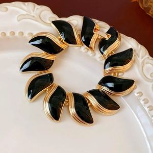Gros plan d'un bracelet vintage en or et noir sur une assiette en céramique