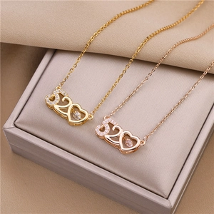 Detail of 520 heart pendants in gold and rose gold finish inside a beige jewelry box