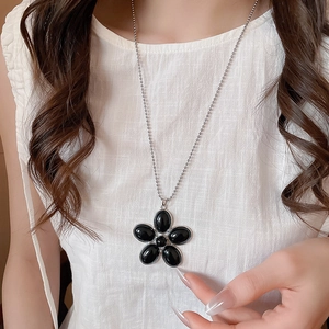 Detail of vintage resin flower pendant necklace with black oval petals on silver bead chain