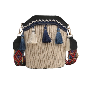 Close-up of beige woven bucket bag featuring blue tassels and geometric strap details