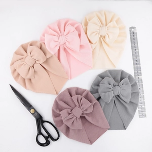Flat lay of baby waffle bow turbans in five soft colors with scale ruler for size
