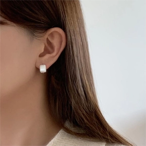 Close-up of elegant square white mother of pearl stud earring worn by a model