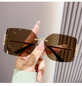 Close-up of rimless square sunglasses with brown gradient lenses and gold metal details