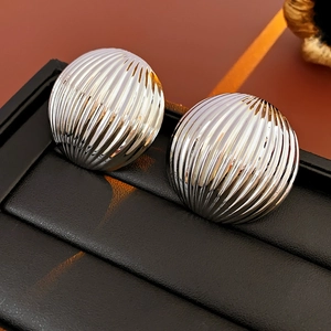 Close-up of silver striped round metal earrings with a textured finish on a black stand