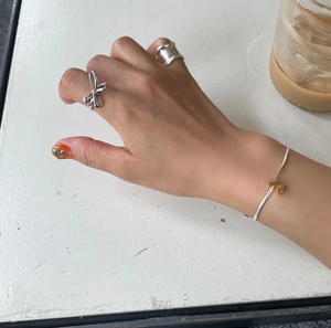 Detail view of 925 sterling silver bow ring and bracelet set worn on a hand
