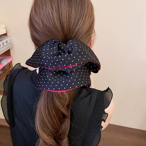 Detail of oversized black and white polka dot hair bow on low ponytail with red edging