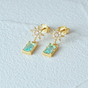 Macro detail of S925 engraved gold-plated silver earrings with star and green sapphire