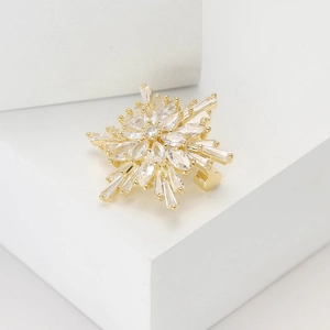 Fashionable gold snowflake brooch with sparkling cubic zirconia on geometric white blocks