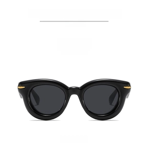 Front view of thick black frame sunglasses with gray lenses and gold rivet accents