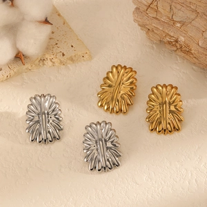 Polished 18k gold and silver floral shell texture earrings on a natural stone background