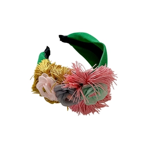Handmade fabric flower headband with tassels and colorful mesh decorations on a wide green band