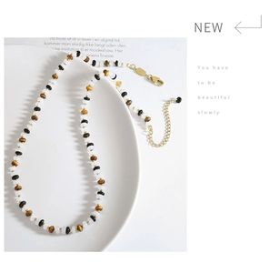 Detail of white jade and tiger eye beaded choker with a gold-plated clasp and chain