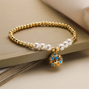 Détail d'un bracelet perlé avec perles dorées, perles blanches et pendentif étoile