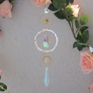 Detail of crystal suncatcher with golden moon and star prisms against pink roses