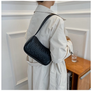 Close-up of black shoulder bag with elegant wavy quilted leather texture and modern design