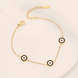 Close-up of golden stainless steel bracelet featuring three evil eye pendants