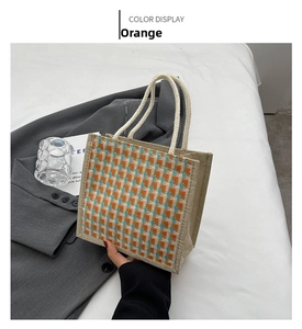 Detailed macro view of orange plaid woven linen tote bag with cream braided rope handles