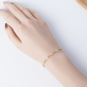 Detail of a gold bracelet with emerald-cut cubic zirconia on a model's wrist