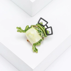 Creative frog brooch with green enamel, black glasses, and crystal details on white background