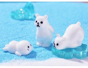 Close-up of resin polar bear and seal figurines on blue sand with ice cube decor
