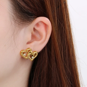 Close-up of 18K gold-plated double heart stud earrings with sparkling diamonds on a model