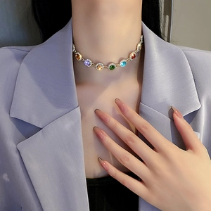 Detailed view of a gold collar necklace featuring vibrant multi-colored crystal pendants