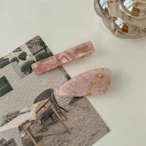 Detail of pink marble acetate hair clip and resin teardrop clip with gold foil flakes
