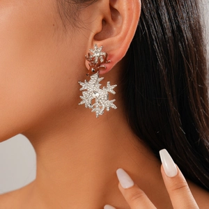 Close-up of reindeer and snowflake earrings with sparkling crystals and brown enamel
