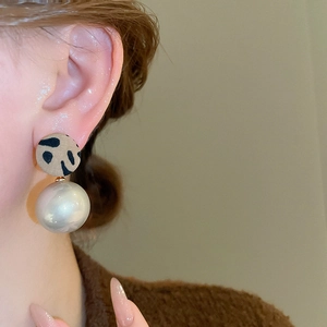 Gros plan détaillé des boucles d'oreilles léopard avec de grandes perles blanches