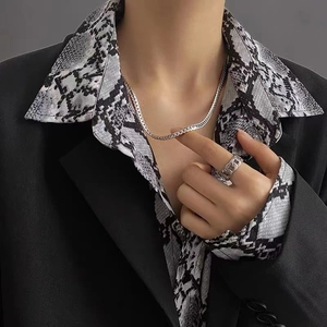 Silver Cuban link necklace and matching ring on model wearing a black blazer and snake shirt
