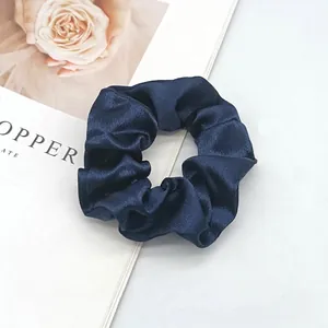Detail shot of navy blue satin scrunchie with silky texture and elegant folds
