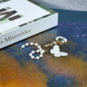Elegant beaded bracelet with white pearls, golden star charms, and a delicate butterfly motif