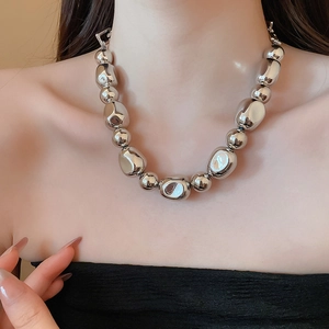 Gros plan d'un collier de perles métalliques argentées irrégulières sur le cou
