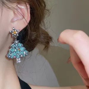 Boucles d'oreilles sapin de Noël avec cristaux et étoile dorée portées par un mannequin