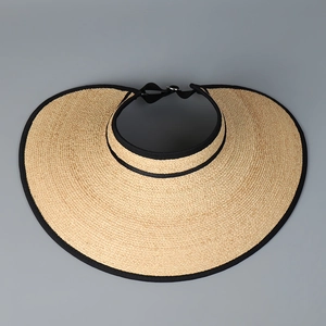 Detail of raffia sun hat weaving texture with wide brim and black edge trim
