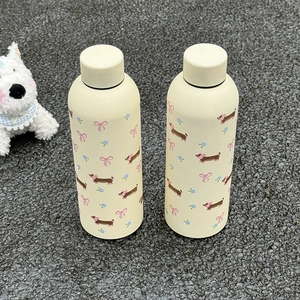 Détail de deux bouteilles isothermes en acier inoxydable crème avec motifs mignons de teckels