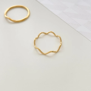 Macro shot of two minimalist gold wave rings with polished finish on a clean background
