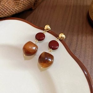 Macro detail of retro resin drop earrings featuring amber wood grain and burgundy beads