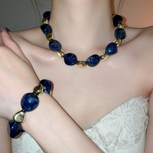 Detail view of acrylic marbled blue beads and gold metal spacers on jewelry set